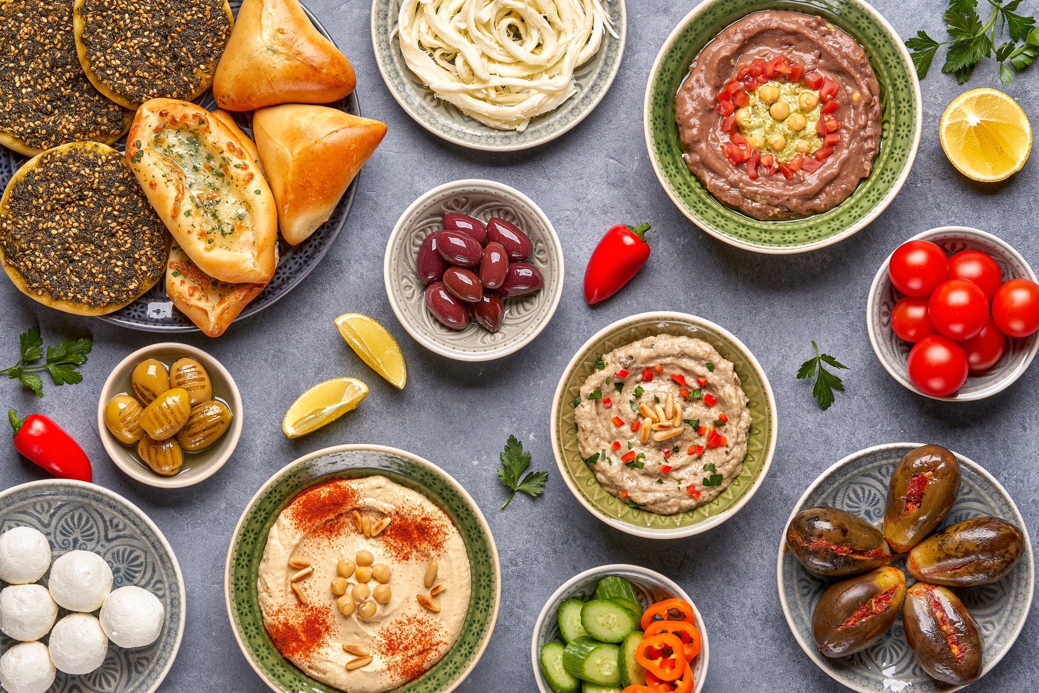 Top view of a middle eastern breakfast with dishes that include makdous, manakish, zaatar, hummus musabaha, olives and cheese